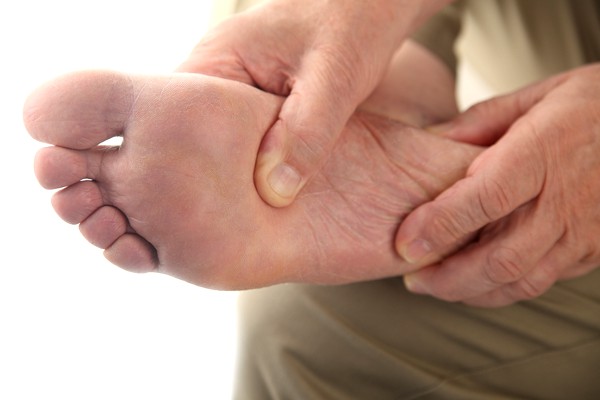 foot-problems-arch-heel-pain-kelowna person holding his foot in pain